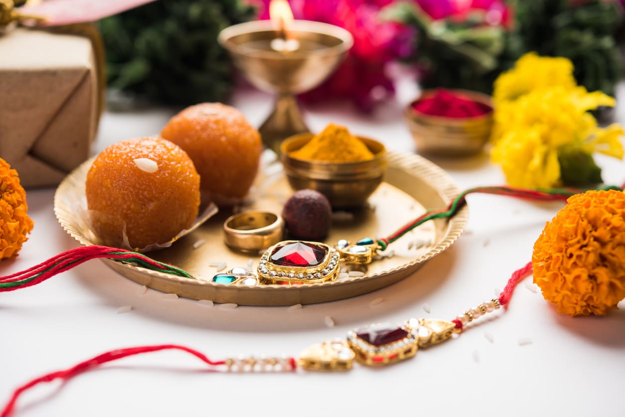 A beautifully arranged Raksha Bandhan thali featuring decorative rakhis, sweets, turmeric, and flowers, set for the sibling celebration.