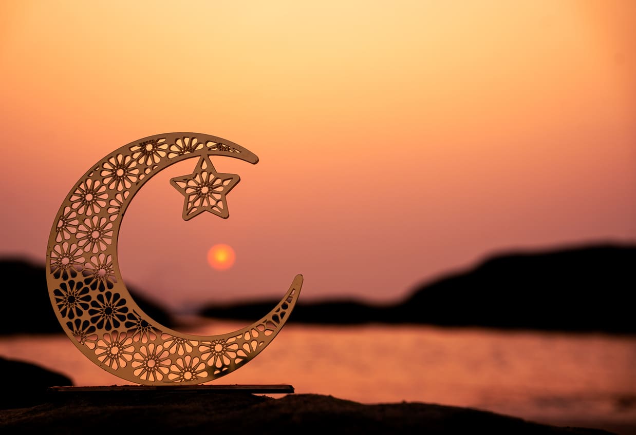 A glowing crescent moon and star against a dusky sky, symbolising the spiritual start of Ramadan.