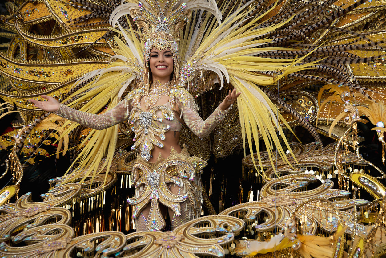 The Queen of the Carnival shines in a breathtaking golden costume adorned with feathers and jewels, leading the grand final parade of Carnival Tuesday with grace and splendor.