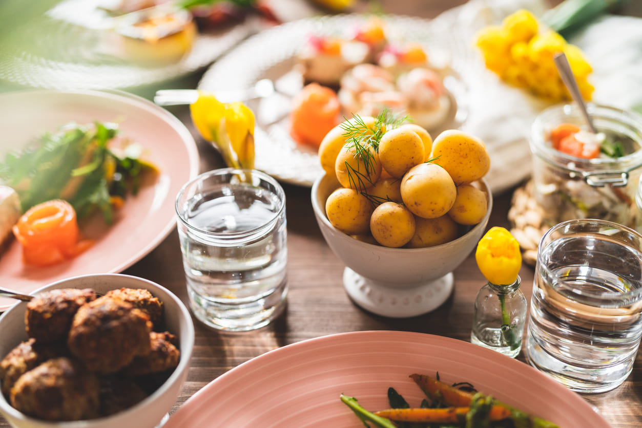 A bright and inviting table set with traditional Swedish Easter foods, fresh flowers, and spring colors, capturing the relaxed mood of Easter Monday.