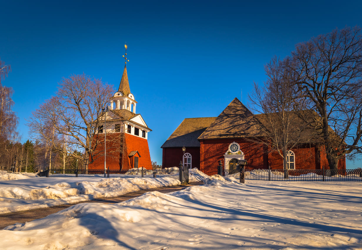 A classic red wooden church in snowy Sweden, warmly lit under a bright blue winter sky, capturing the peaceful spirit of Epiphany.