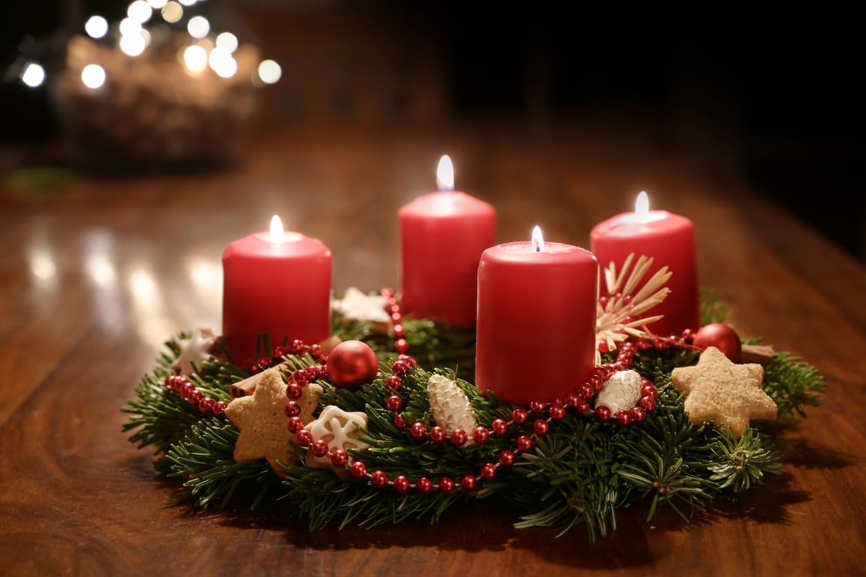 A festive Advent wreath with all four red candles lit, surrounded by cookies, pinecones, and ornaments, symbolizing the arrival of Fourth Advent Sunday in Sweden.