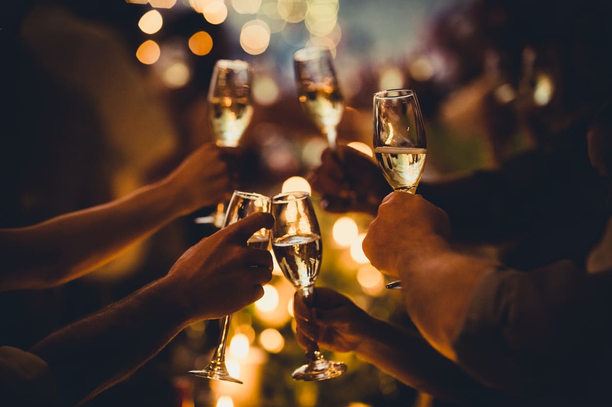 A group of people toasting with champagne glasses, surrounded by warm lights and festive atmosphere on New Year's Eve.