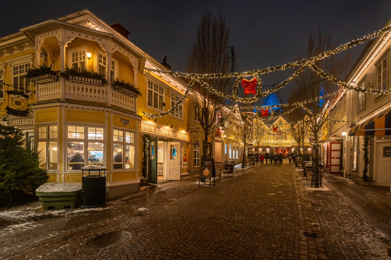 A warmly lit Swedish street decorated with Christmas lights and red bows, creating a festive and cozy holiday atmosphere.