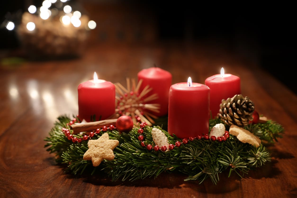 A beautifully decorated Advent wreath with three lit red candles, cookies, pinecones, and ornaments, symbolizing the joy of Third Advent Sunday in Sweden.