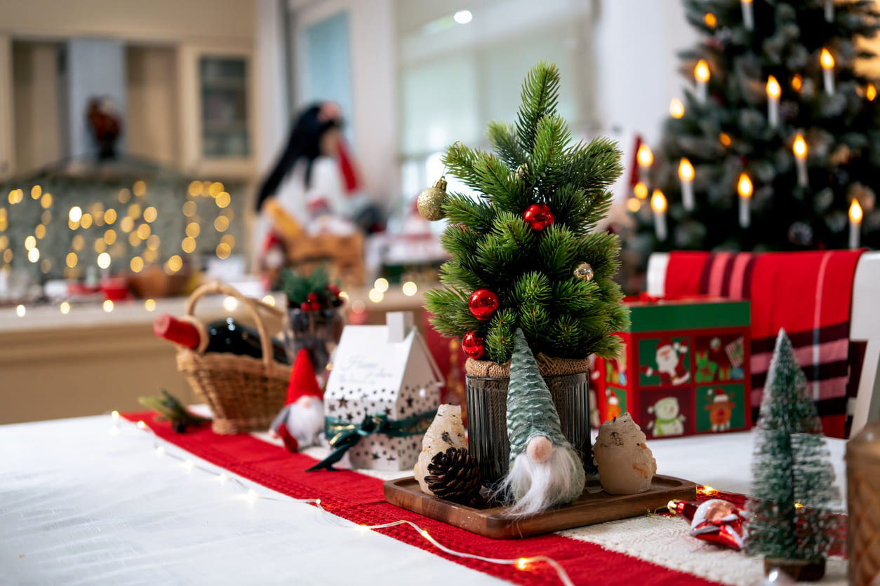 A beautifully decorated Christmas table with miniature trees, ornaments, and warm lights, capturing the festive spirit of Christmas Eve in Thailand.