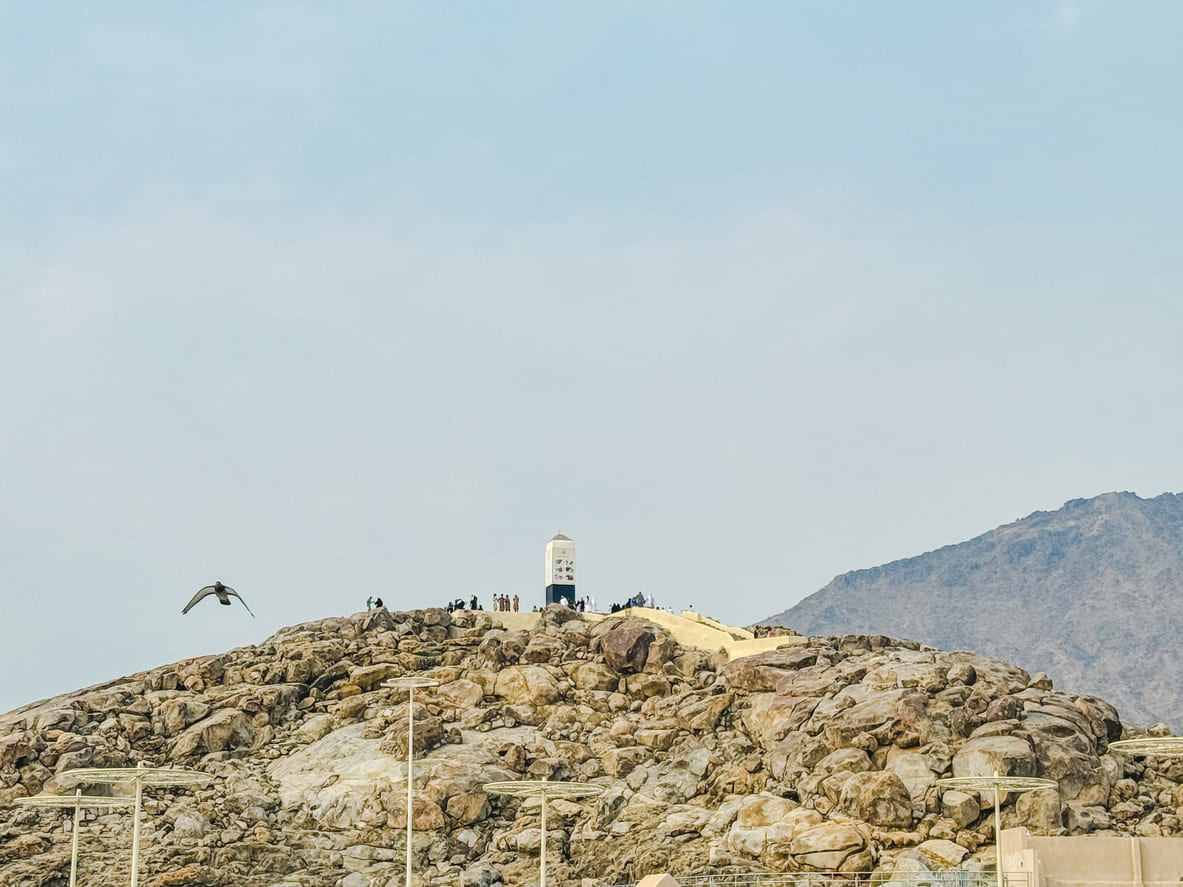 Mount Arafat with pilgrims gathered at its peak, capturing the spiritual essence of Arafat Day during Hajj.