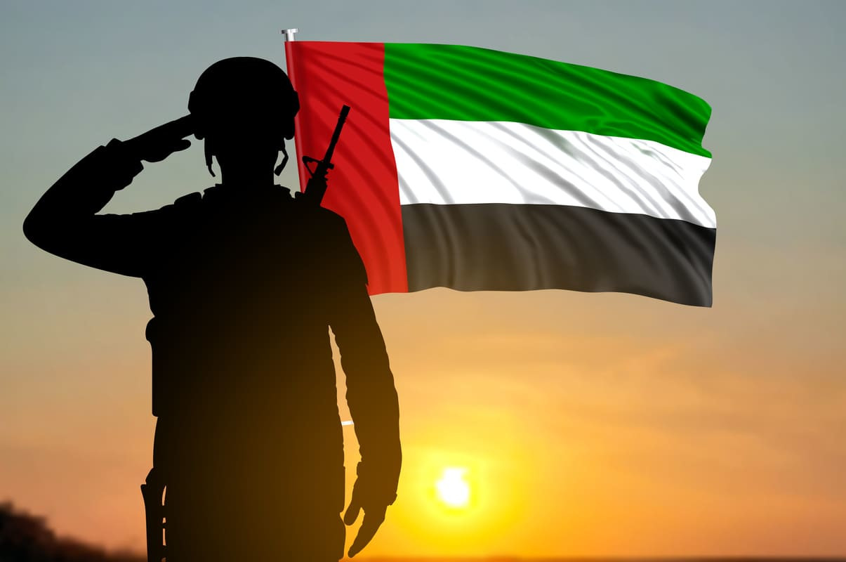 A soldier saluting the UAE flag at sunset, symbolizing respect and remembrance on Commemoration Day.