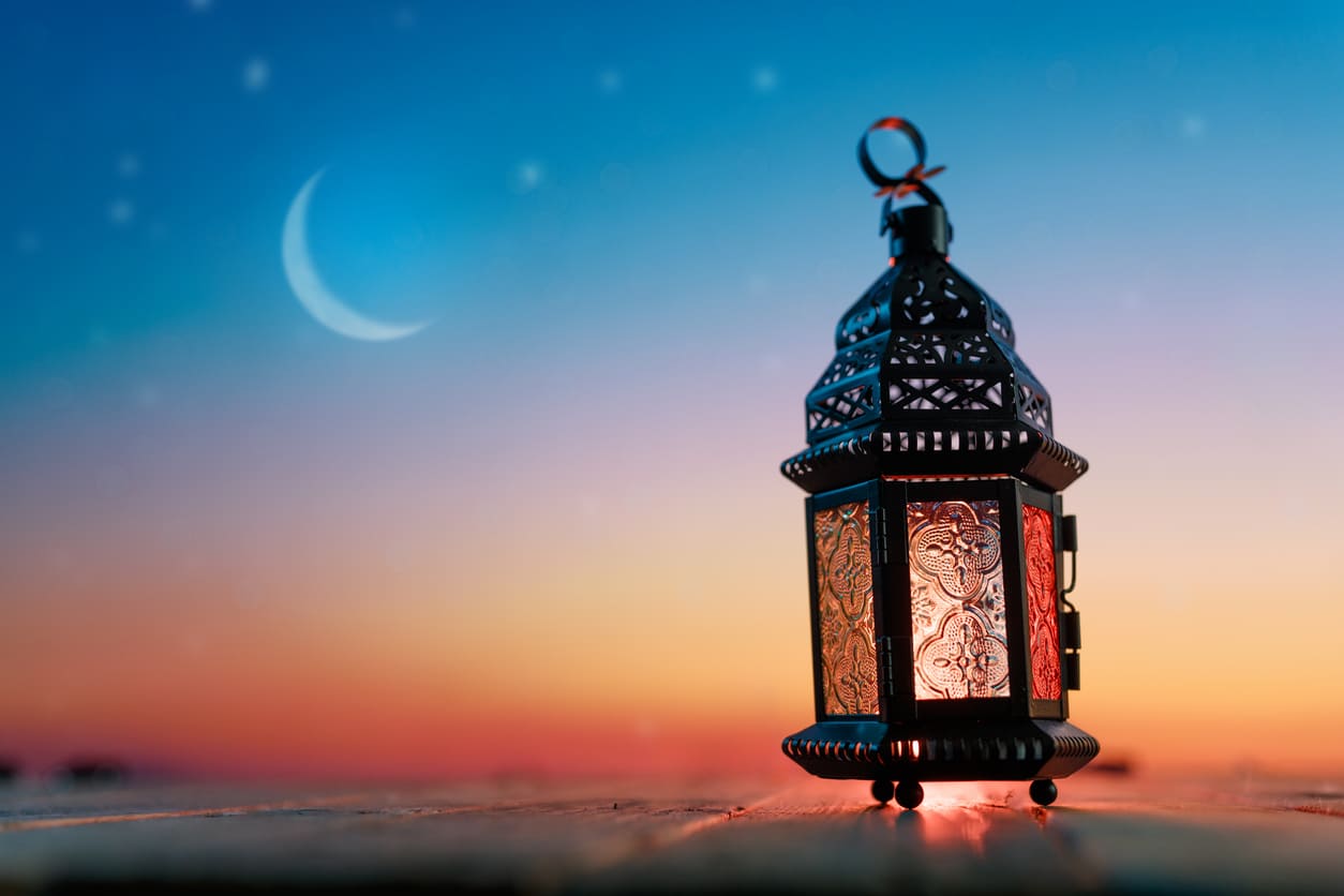 The sighting of the crescent moon, signaling the start of Ramadan, with a traditional lantern symbolizing the holy month.