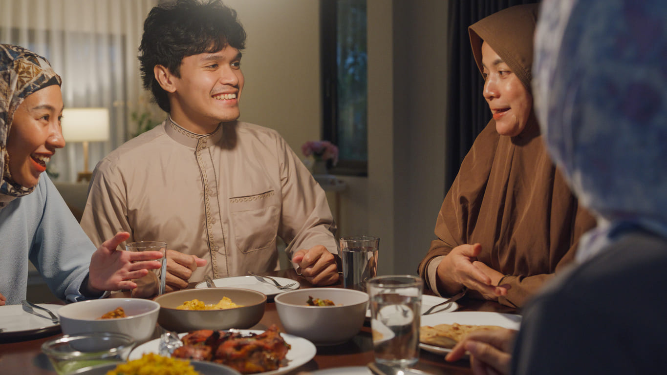 A family gathers with smiles, sharing a festive meal in celebration of Eid-ul-Fitr.