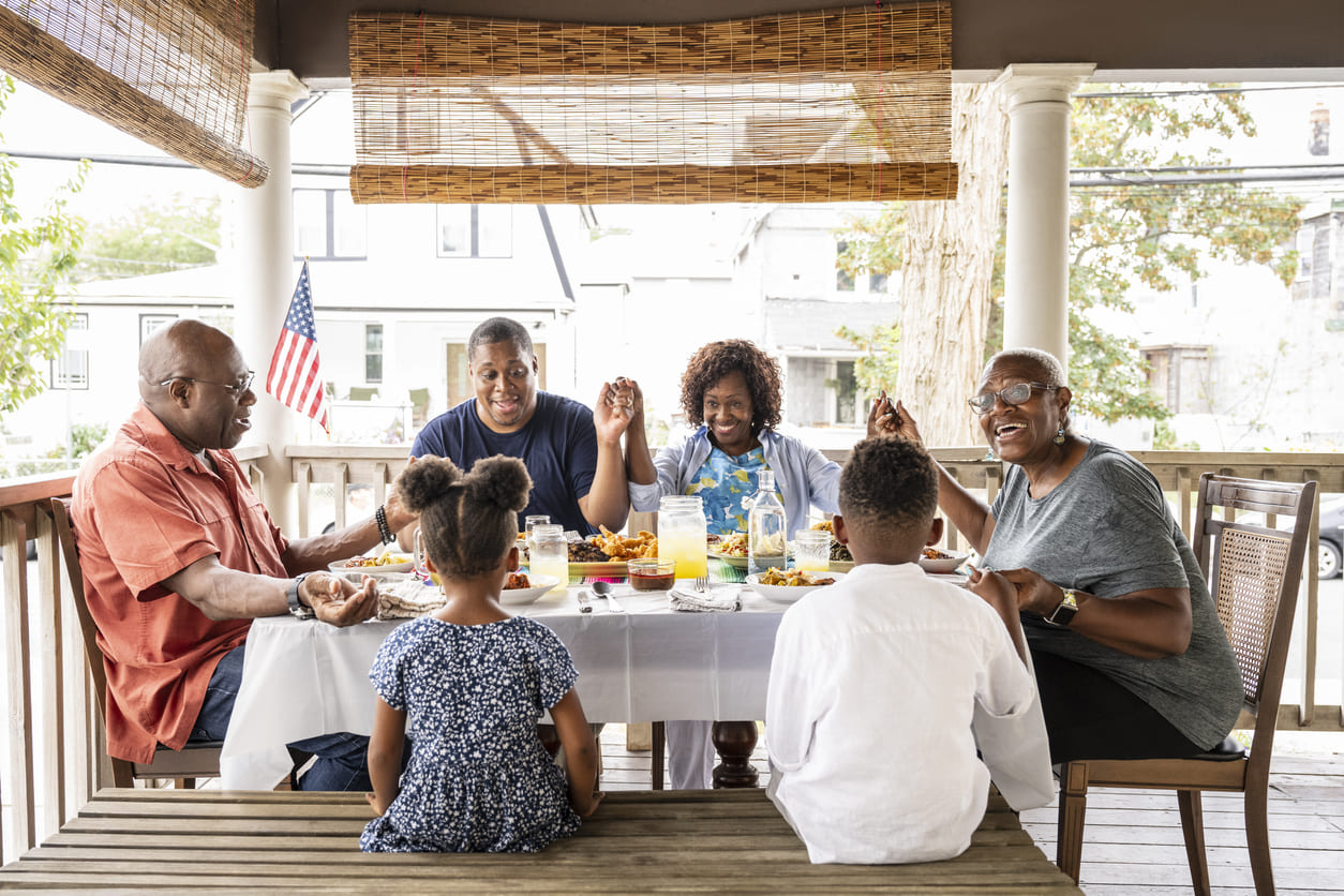 A family gathers on a porch, relaxing and sharing a meal in a moment of togetherness.